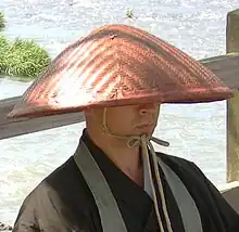 A Buddhist monk wearing a takuhatsugasa.