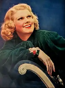 Color photo of Harlow sitting on a chair, leaning on her arm