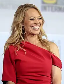 A photograph of Jeri Ryan in 2019; a white woman with a red top and long blond hair and a wide smile