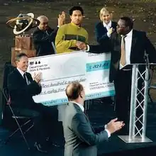 Jeshi accepts an oversized cheque for £324.84 from several presenters