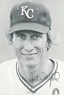 A man in a light baseball uniform and dark hat