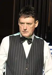 A man wearing a dark waistcoat and bow tie