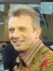 Joe Montana smiling and wearing a green and red patterned collared shirt.