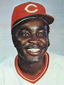 A man in a white baseball jersey and red cap