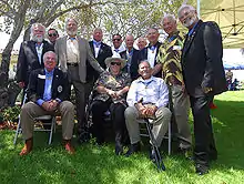 a group of men stand or sit, posing for a photo