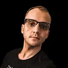 Portrait of Jackson, wearing glasses and in front of a black background