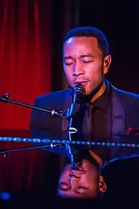 A man with his eyes closed, playing the piano, in front of a microphone