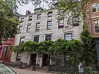 A pair of mirror-image granite row houses with mostly unadorned, flat facades