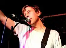 Vanderslice raising his arm onstage and singing into a microphone