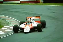 Frontview of a red-and-white McLaren racing car driving through a corner during a race