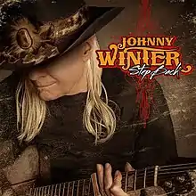 Johnny Winter, wearing a broad-brimmed hat and playing a guitar