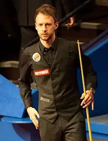 Judd Trump stood holding a cue