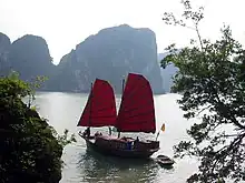 Traditional red sails on Hạ Long style's boat contrast with blue water surface