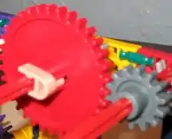  A large red K'Nex gear meshed with a smaller gear.