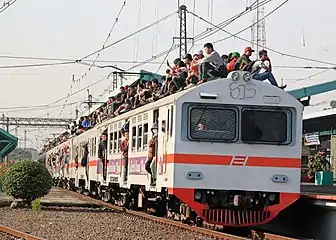 A crowded KRL Jabotabek electric multiple-unit train with passengers riding on the outside in Jakarta, Indonesia