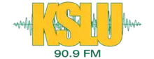 Large yellow block letters K S L U, trimmed in green, with a green waveform behind them. Beneath in a sans serif is the text "90.9 FM" in green.