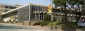  A large TV station building. The building has many windows and a large awning runs parallel to one side. A small sign out front and a large sign on the side of the building both say KWQC TV 6