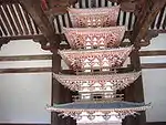 Wooden miniature pagoda with white walls and vermillion red beams.