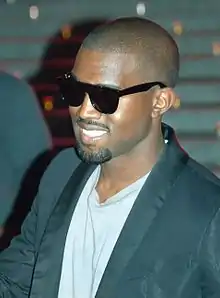 A man dressed in a white shirt and black suit wearing sunglasses.