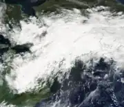 A satellite image of an extended area of clouds oriented southwest to northeast across the Great Lakes region of the United States and Canada