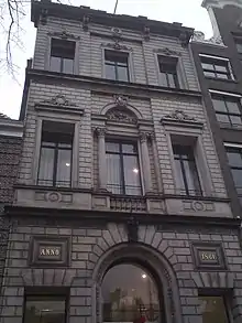 Three-story building in grey stone with the text "Anno 1861." on the facade