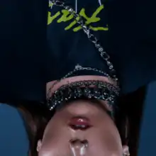 An upside-down shot of Kenya Grace with chains around her neck