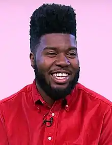 Khalid smiling while wearing a red shirt