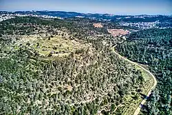 To the left are the remains of the village (in the forest clearing on the spur), above the riverbed. Up the riverbed is the village spring and the villages of Ein Rafa and Ein Nakuba.