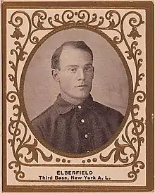 A sepia-toned image of a dark-haired man in a dark shirt who sits facing at an angle toward the right