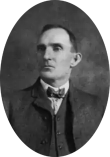 Bust portrait of a man in a late nineteenth century, three-piece suit and bow-tie, looking off to his right