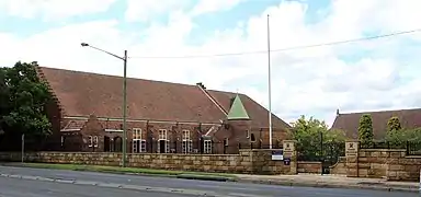 View from Pacific Highway, with the War Memorial Gates in the foreground, the John Williams Memorial Hall on the left, and the Main Building on the right.