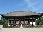 Wooden building with white walls and a trapezoidal roof.