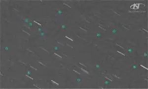 A telescope image showing stars as streaks and Kosmos 1408 debris as circled dots