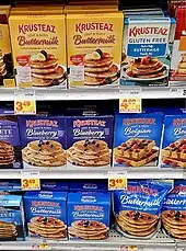 Grocery store shelf with dozens of boxes of pancake mix.