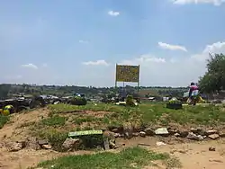 A community painted sign, reading "Kya Sands Formal Settlement, Please RDP"