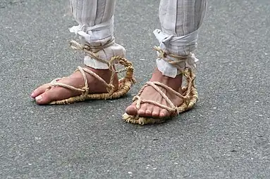 These waraji are made as in the instructions above, but two small loops are woven on each side (instead of one big foot-crossing loop), and the leftover-warp loops at the heel are retained. A separate rope is then woven through these loops to attach the waraji to the foot.