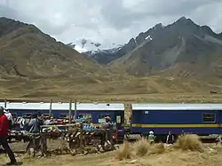 The train the Belmond Andean Explorer at La Raya Station with market stalls and the mountain Chimpulla in the background, Layo District-Santa Rosa District