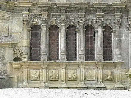 Five of the ossuary windows. Note stoup with "Ankou" on left and carvings below each window