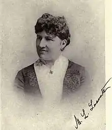 Photograph of a short-haired woman wearing a highly decorative frock featuring trapunto quilting, over a lace bodice.