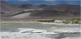 Mountains rising above a water surface with white terraces