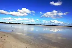 The photo shows Lake Beeac and the sky above it. The surface of the water is mirror-like, it reflects the blue sky and the clouds in it.