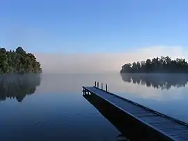 Image 14Lake MapourikaPhoto credit: Richard PalmerMorning mist on Lake Mapourika, a lake on the West Coast of New Zealand's South Island. It is the largest of the west coast lakes, a glacier formation from the last ice age. It is filled with fresh rain water which runs through the surrounding forest floor, collecting tannins and giving it its dark colour.