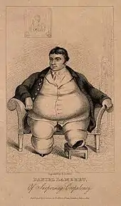 Smartly dressed fat man with dark hair sitting on a chair