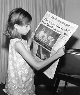 Image 21A girl reading a 21 July 1969 copy of The Washington Post reporting on the Apollo 11 moon landing (from Newspaper)