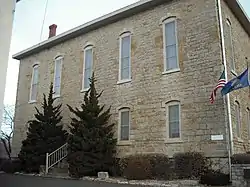 A stone building can be seen from the street, with a flagpole next to it; this was one of the buildings at Lane University in Lecompton, Kansas