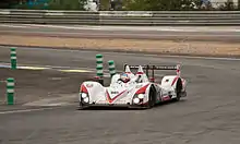 A red and white LMP2 sports prototype being turned around a corner on a racing track