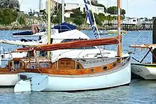 Cruising catboat showing classical rudder design and wire stays supporting the mast