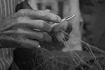 The hands of a fisherman working with his fishing net.