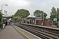 A view, towards Bidston, of the platforms, footbridge and level crossing.