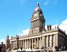 Large, rectangular, extremely ornate, marble building with many columns and other decorative details, including a columned tower on the roof.